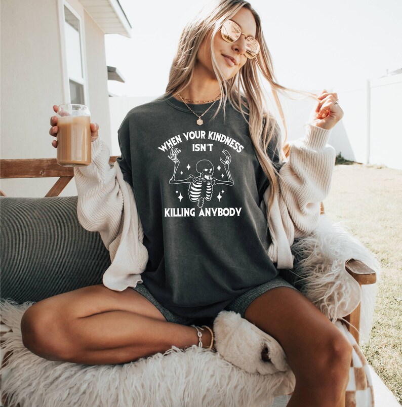 May include: A dark gray sweatshirt with a white skeleton graphic and the text "When your kindness isn't killing anybody".
