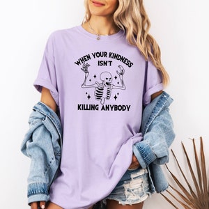 May include: A lavender t-shirt with a black skeleton graphic and the text "When your kindness isn't killing anybody".