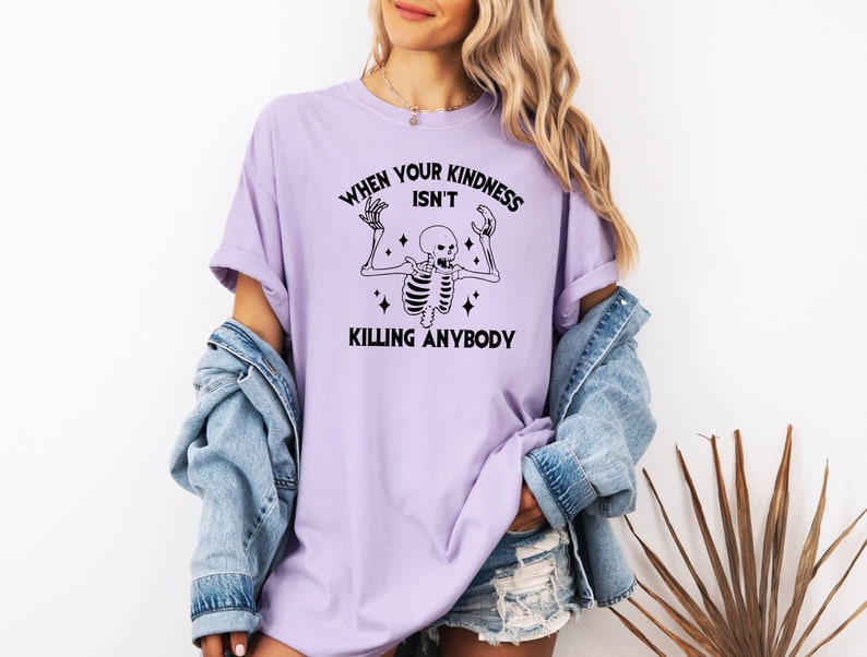 May include: A lavender t-shirt with a black skeleton graphic and the text "When your kindness isn't killing anybody".