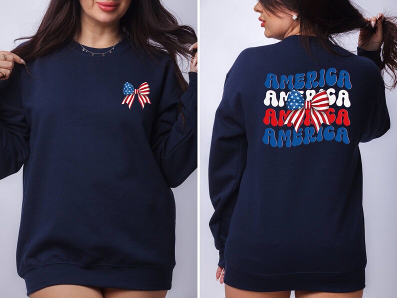 K&ouml;nnte beinhalten: Ein marineblauer Sweatshirt mit einer rot-wei&szlig;-blauen Schleife mit Sternen auf der Vorderseite und dem Wort "AMERICA" viermal in einer Retro-Schrift auf der R&uuml;ckseite.
