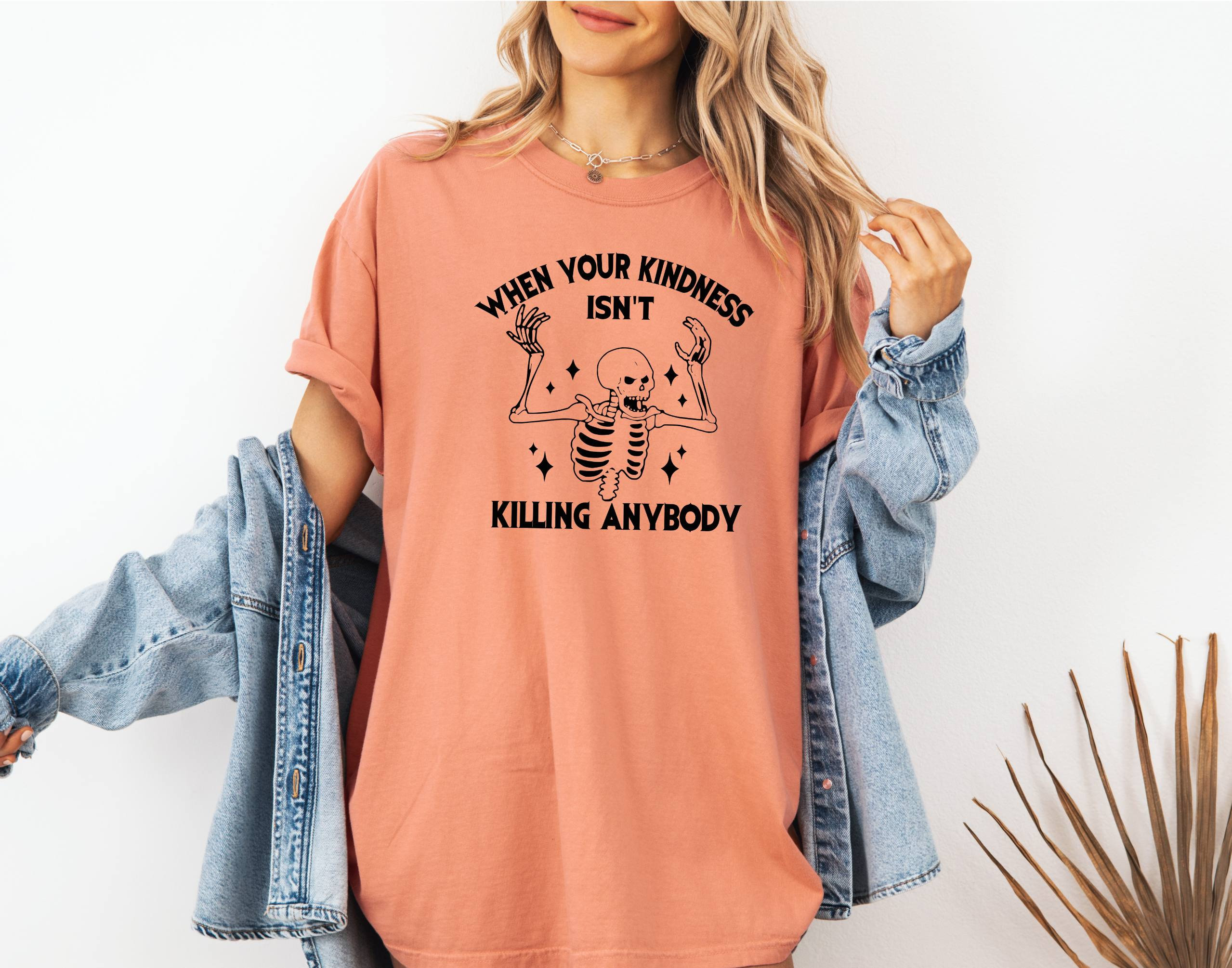 May include: A peach-colored t-shirt with a black skeleton graphic and the text "When your kindness isn't killing anybody".