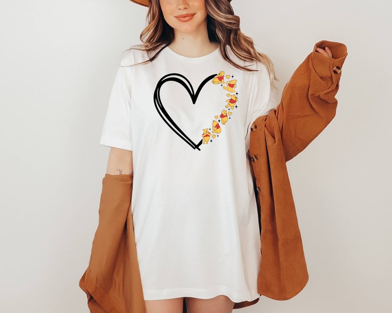 May include: White t-shirt with a black outline of a heart and Winnie the Pooh characters forming the heart shape.