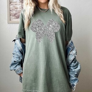 May include: A green oversized t-shirt with a silver glitter bow design.