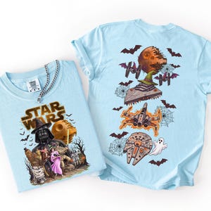 May include: A light blue t-shirt featuring a Star Wars graphic on the front with Darth Vader, Chewbacca, Han Solo, and Princess Leia. The back of the shirt displays a Star Wars themed Halloween print with a Death Star, X-wing, and Millennium Falcon.