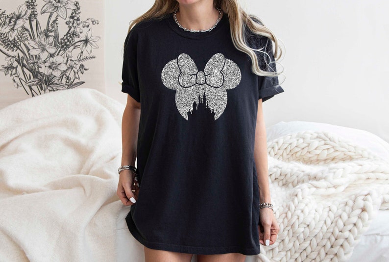 May include: Black t-shirt with a silver glitter design of a bow with a castle inside.