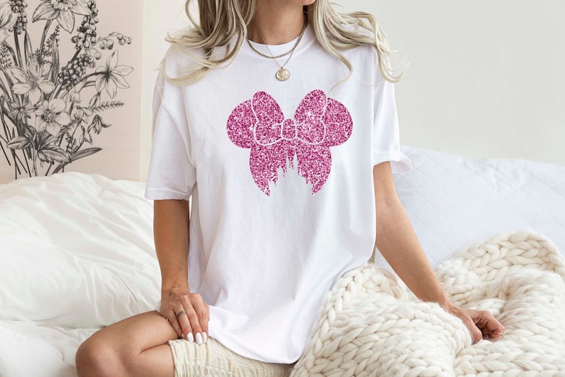 May include: White t-shirt with a pink glitter bow and castle design.