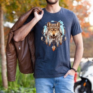Pode incluir: Uma camiseta azul marinho com um gr&aacute;fico de uma cabe&ccedil;a de lobo dentro de um apanhador de sonhos com penas. O apanhador de sonhos &eacute; rodeado por respingos de aquarela azul e branca.