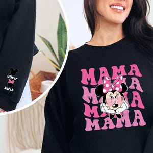 Puede incluir: Sudadera negra con un gr&aacute;fico rosa de Minnie Mouse y el texto "MAMA" repetido cuatro veces. La sudadera tiene cuello redondo y mangas largas.