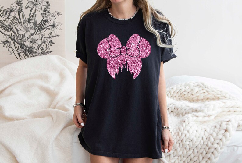 May include: Black t-shirt with a pink glitter bow and castle design.