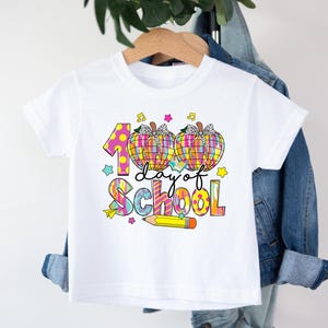 May include: White t-shirt with a colorful graphic that says "100 day of school" with two pumpkins and a pencil.