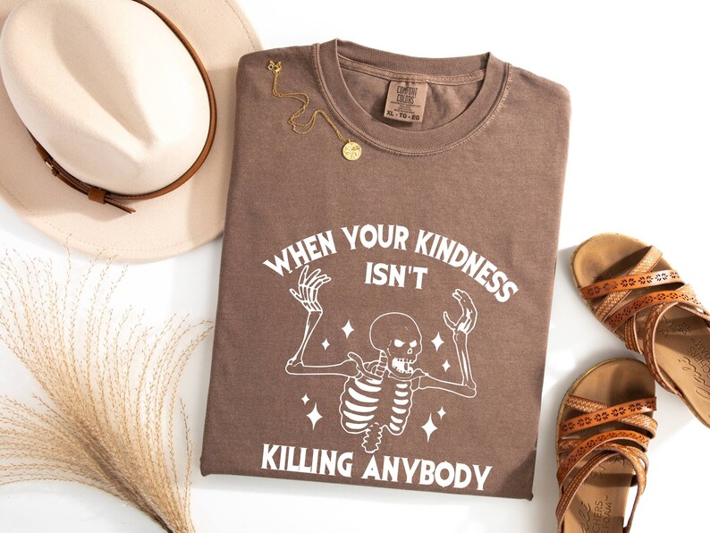 May include: A brown t-shirt with a white skeleton graphic and the text "When your kindness isn't killing anybody".