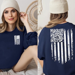 May include: Navy blue sweatshirt with a distressed white American flag design on the front and back. The back features a QR code in place of the stars. The sweatshirt is a crew neck style.