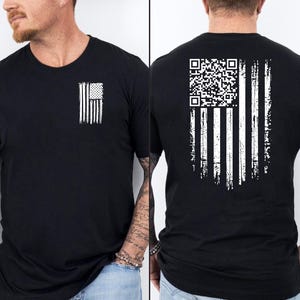 May include: Black crew neck t-shirt with a distressed white American flag design on the front and back. The back features a QR code integrated into the flag's stripes. A casual, patriotic apparel item.