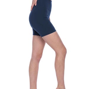 May include: Solid navy blue high-waisted athletic shorts featuring a fitted silhouette that extends to the mid-thigh. The shorts are constructed with a wide, supportive waistband and a smooth, seamless appearance, providing a clean look.