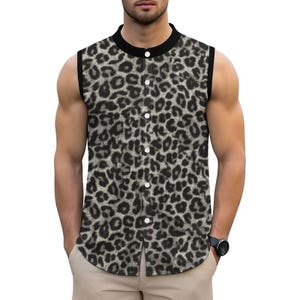 Puede incluir: Camisa sin mangas con cuello y ribete negros. Presenta un estampado de leopardo en tonos grises y negros. La camisa tiene cuello mandarín y botones blancos.