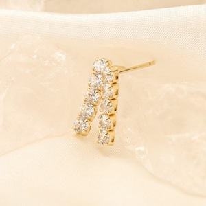 Op de afbeelding: Een paar gouden oorbellen met een dubbele rij heldere zirkonia-stenen.