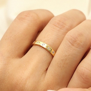 K&ouml;nnte beinhalten: Ein goldener Ring mit kleinen, klaren Steinen, die in einem Sternmuster eingefasst sind.
