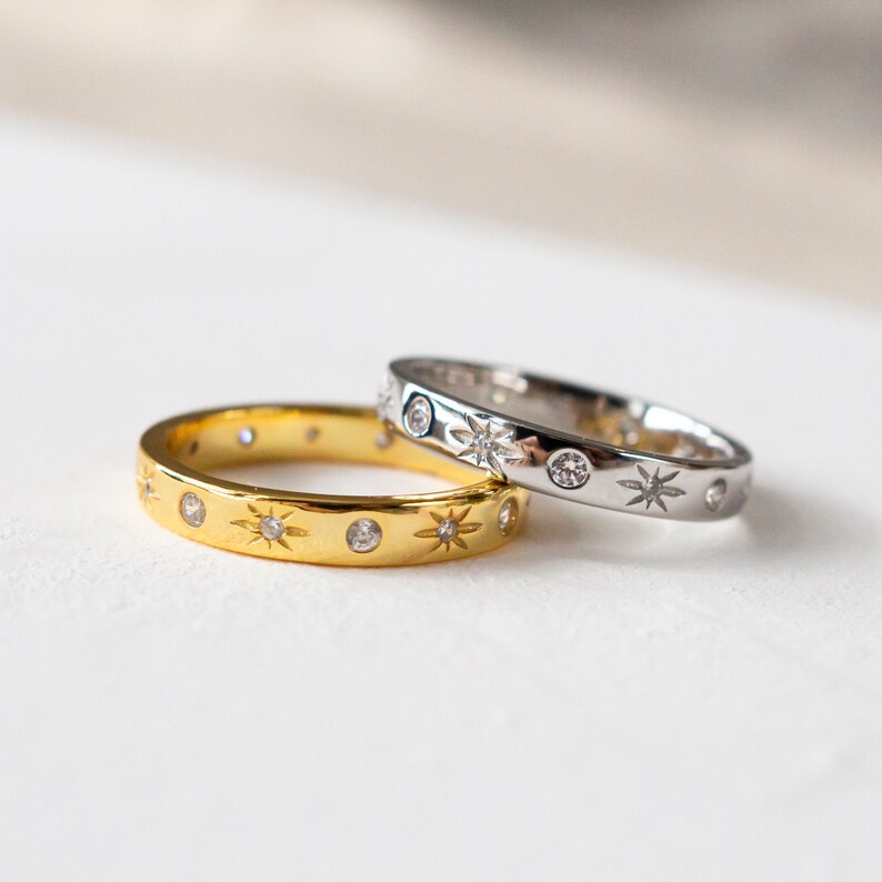 K&ouml;nnte beinhalten: Zwei d&uuml;nne Ringe aus Gold und Silber mit einem Sternenmuster und kleinen klaren Steinen.
