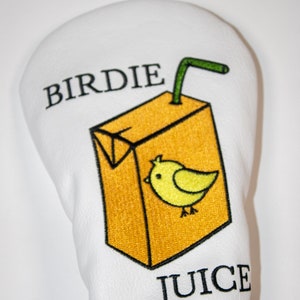 May include: White golf headcover with an embroidered image of a yellow juice carton with a green straw and a yellow bird. The text "BIRDIE JUICE" is embroidered on the headcover.