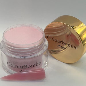 Puede incluir: Un tarro de polvo acrílico rosa con la etiqueta "ColourBombe Acrylics". Se muestra una muestra del polvo en una punta de uña.