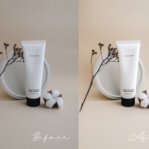 May include: A white tube of 2ND SKIN  'Derma Peel Gel Tone Up Boost' face cream on a white round platform with a small cotton flower next to it. The background is a light beige color.