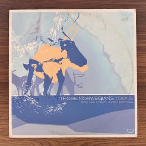 Pode incluir: Uma capa de disco de vinil quadrada com uma ilustração estilizada de uma rena em tons de azul e laranja sobre um fundo azul claro. O texto diz "THOSE NORWEGIANS TOONS" e "Terry Lee Brown Junior Remixes" em fonte branca.