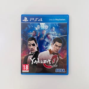 以下が含まれることがあります： PlayStation 4用ゲームソフト「龍が如く0 誓いの場所」の青いプラスチックケース。パッケージにはスーツを着た複数の人物が描かれており、その中には眼帯をした男性も含まれています。タイトルは白と赤の文字で記され、角には赤いPEGI 18のレーティングマークがあります。