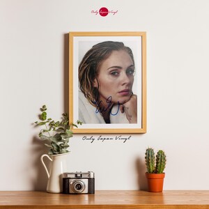 Op de afbeelding: Een ingelijste foto met een portret van Adele, gesigneerd met blauwe inkt. De foto is geplaatst in een licht houten frame. Het Only Japan Vinyl-logo is zichtbaar rechtsboven en in het midden onderaan.