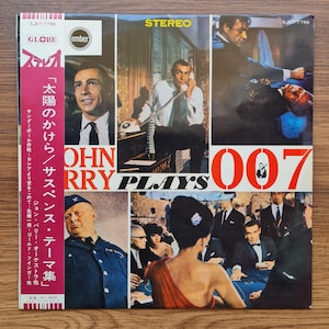 May include: A vintage vinyl record album cover featuring images of a man in a suit, a phone, and a casino scene. The album title is "John Barry Plays 007" with Japanese text and the word "STEREO" in yellow.