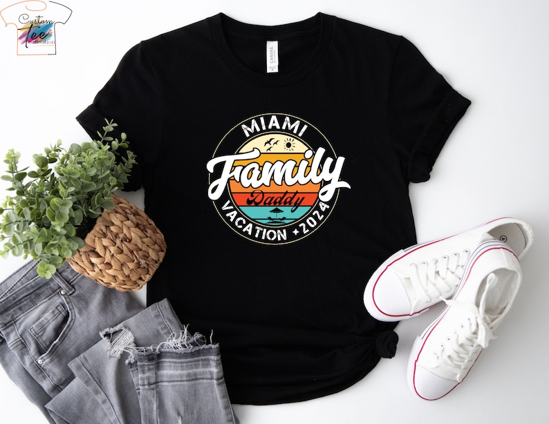 May include: Black t-shirt with a vintage-style graphic that says "Miami Family Vacation 2026" with a palm tree and sun graphic. The text "Daddy" is in a smaller font and is located below the main text.