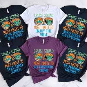 May include: A collection of crew neck t-shirts with the text "Cruise Squad" and various phrases like "Most Likely to Be the Smartest in the Group." Each shirt features sunglasses with a beach scene. Colors include navy, white, and purple.