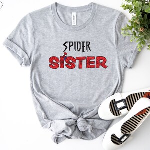 Puede incluir: Camiseta gris con el texto "SPIDER SISTER" en negro con un gr&aacute;fico rojo de Spider-Man en la "S" de hermana.