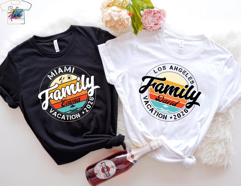 May include: Two black and white t-shirts with a retro-style graphic design. The graphic features a circle with the word "Family" in a stylized font, a sunset, and the text "Miami Vacation 2026" and "Los Angeles Vacation 2026".
