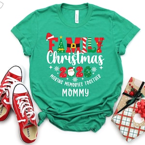 May include: A green t-shirt with the words "FAMILY Christmas 2026" in a festive design, along with the phrase "MAKING MEMORIES TOGETHER MOMMY." Red trainers and wrapped gifts with bows are also in the image.