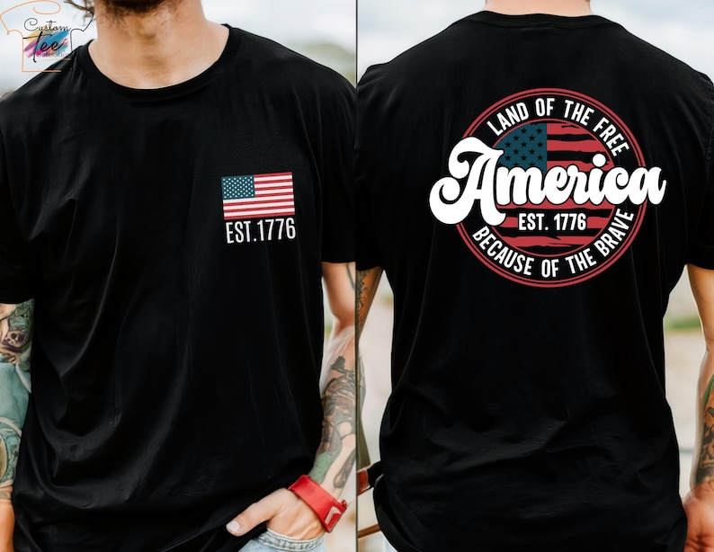May include: A gray t-shirt with a small American flag on the front and a larger circle design on the back. The circle design features a larger American flag, the text "Land of the Free", "America", "Est. 1776", and "Because of the Brave".