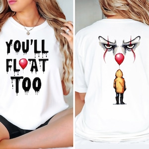 May include: White t-shirt with black dripping text that reads "You'll Float Too" on the front and a graphic of Pennywise the clown's eyes and a red balloon on the back.