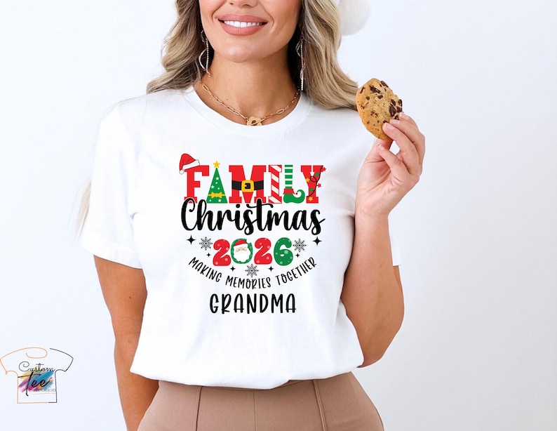 May include: White t-shirt featuring a Christmas graphic. The design includes the words "FAMILY Christmas 2026" in red, green, and black, with festive elements like a Santa hat, Christmas tree, and elf shoes. The text "Making Memories Together Grandma" is also included.
