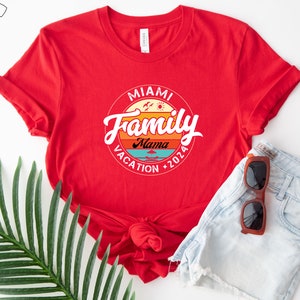 May include: Red t-shirt with a white circle graphic that says "Miami Family Vacation 2026" with a sunset design and the word "Mama" in the center.