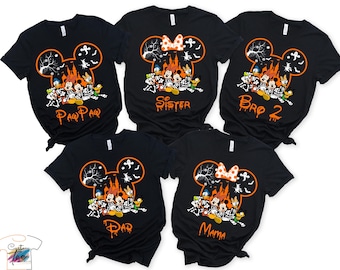 May include: Five black short-sleeve t-shirts featuring a large orange Mickey Mouse ear outline filled with a Halloween scene of a castle, ghosts, bats, and Disney characters in skeleton costumes. Text includes Paw Paw, Sister, Bro 2, Dad, and Mama.