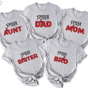Puede incluir: Cinco camisetas grises con un gr&aacute;fico de Spider-Man y las palabras "Spider Dad", "Spider Mom", "Spider Aunt", "Spider Sister" y "Spider Bro" impresas en ellas.