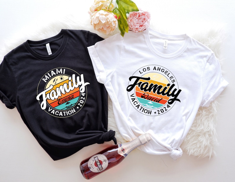 May include: Two black and white t-shirts with a retro-style graphic design. The graphic features a circle with the word "Family" in a stylized font, a sunset, and the text "Miami Vacation 2024" and "Los Angeles Vacation 2024".