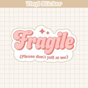 May include: A pink and white vinyl sticker with the word "Fragile" in a retro font. The text "(Please don't yell at me)" is written below the word "Fragile".