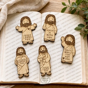 May include: Five light brown wooden cutouts of a cartoon figure with a beard, each featuring engraved text. The figures display phrases including Jesus Loves You, Jesus Is With You, and Don't Worry I've Got You, along with heart and cross icons.