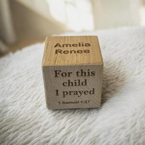 Baby holding personalized wooden birth announcement block with engraved teddy bear, name initial, and birth details