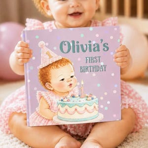 May include: A square hardcover book with a light purple cover featuring a cartoon illustration of a baby wearing a pink party hat and blowing out a candle on a birthday cake. The text reads Olivia's First Birthday in dark teal lettering.