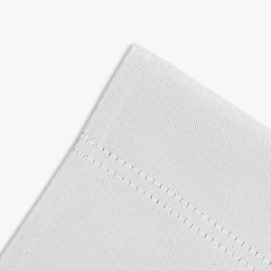 May include: Close-up of a white fabric corner with two parallel rows of stitching. The fabric has a subtle texture and a clean, minimalist aesthetic. The stitching is also white, blending seamlessly with the fabric.