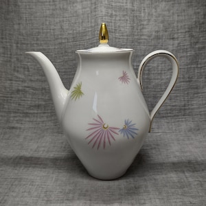 Könnte beinhalten: Weiße Porzellan-Teekanne mit goldenem Deckel und Henkel. Die Teekanne hat ein Blumenmuster mit rosa, blauen und grünen Blumen.