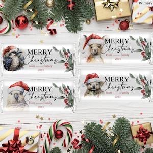 Puede incluir: Cuatro barras de chocolate con temática navideña con ilustraciones de animales. Cada barra presenta el texto "MERRY Christmas" y "From Family 2023". Las ilustraciones incluyen un kookaburra, una llama, una cacatúa y un koala, todos con gorros de Papá Noel.