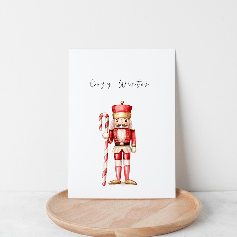 May include: A watercolour illustration of a red and gold nutcracker holding a candy cane. The text "Cozy Winter" is written above the nutcracker.
