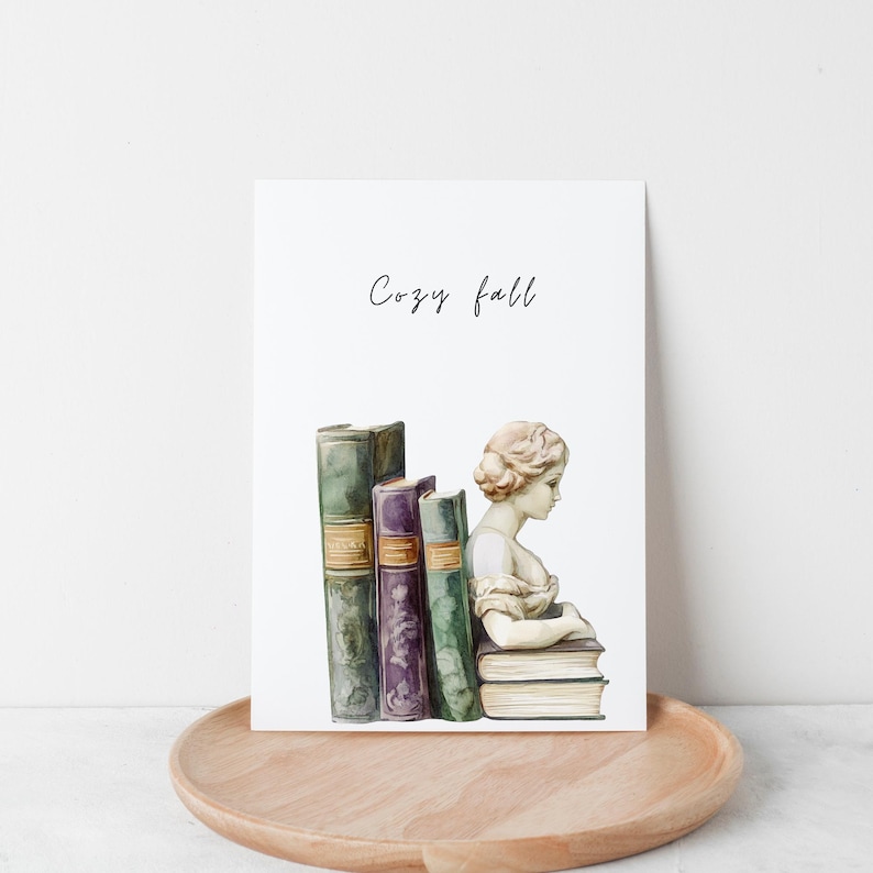 Op de afbeelding: Een aquarel-illustratie van een boekenlegger met een vrouwenbuste die een stapel boeken vasthoudt. De tekst "Cozy fall" staat boven de boekenlegger.